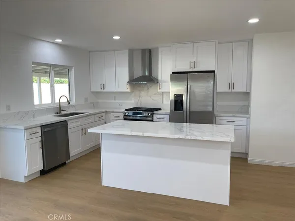 a kitchen with kitchen island granite countertop stainless steel appliances a sink a stove a refrigerator and cabinets
