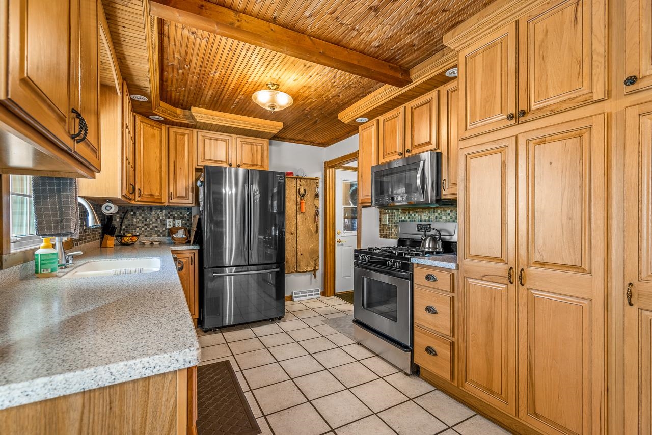 17097 Goodrich Road Davis, IL 61019 - Photo 13 of 45 a kitchen with stainless steel appliances granite countertop a refrigerator a stove and a sink with wooden cabinets