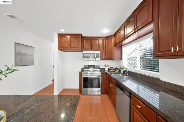 a kitchen with stainless steel appliances granite countertop a stove a sink and a refrigerator