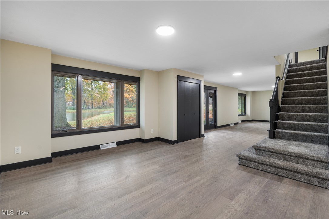 2201 Ridgewood Road Medina, OH 44256 - Photo 12 of 50 Unfurnished living room featuring light wood-style flooring, plenty of natural light, and stairs