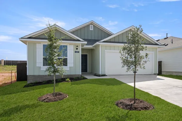 a house that has a clock tower in the middle in front of a yard