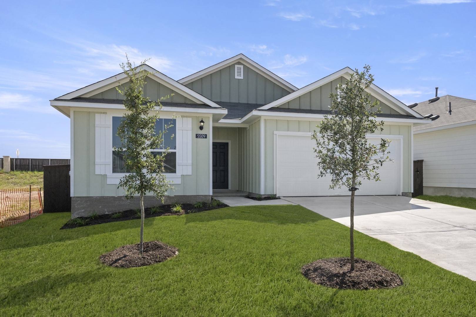 a house that has a clock tower in the middle in front of a yard