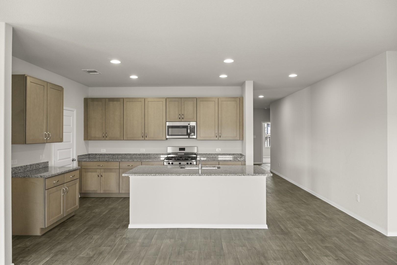 5509 Sacra Cove Austin, TX 78747 - Photo 21 of 38 a large kitchen with stainless steel appliances granite countertop a stove a sink a refrigerator and white cabinets with wooden floor