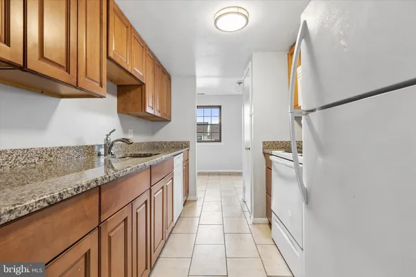 a kitchen with granite countertop a sink a stove top oven and cabinetry