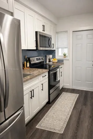 a kitchen with granite countertop a refrigerator stove and microwave