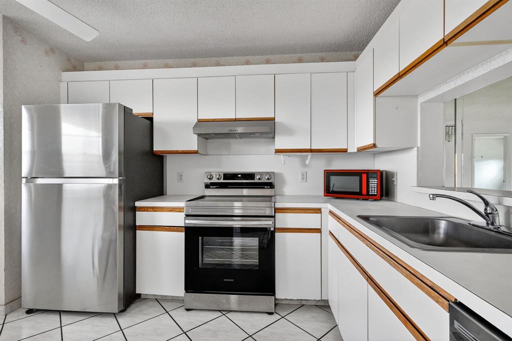 650 Southwest 124th Terrace, Unit 404P Pembroke Pines, FL 33027 - Photo 9 of 26 a kitchen with a refrigerator sink and cabinets