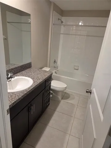 a bathroom with a granite countertop sink a toilet a mirror and shower