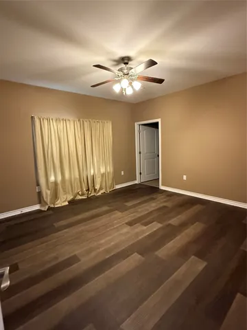 a view of an empty room with window and chandelier fan