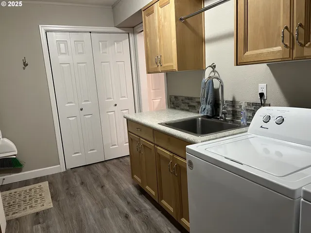 a kitchen with stainless steel appliances a stove a refrigerator a sink a center island and wooden floor