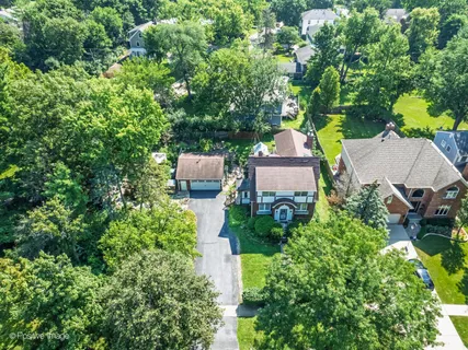 an aerial view of a house with outdoor space and trees all around