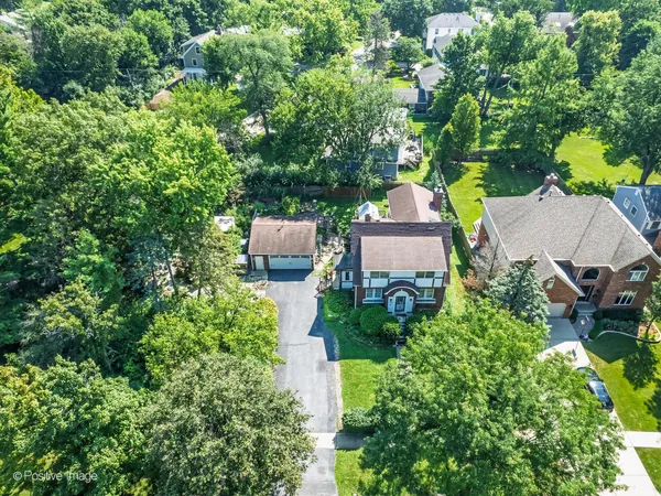 an aerial view of a house with outdoor space and trees all around