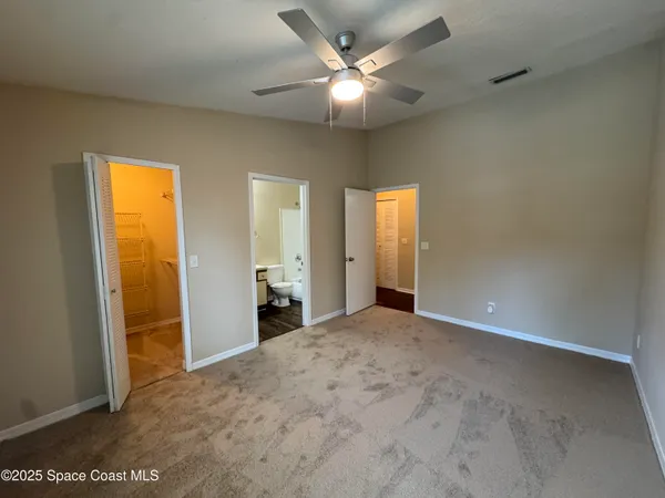an empty room with closet and a chandelier fan
