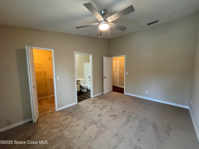 an empty room with closet and a chandelier fan