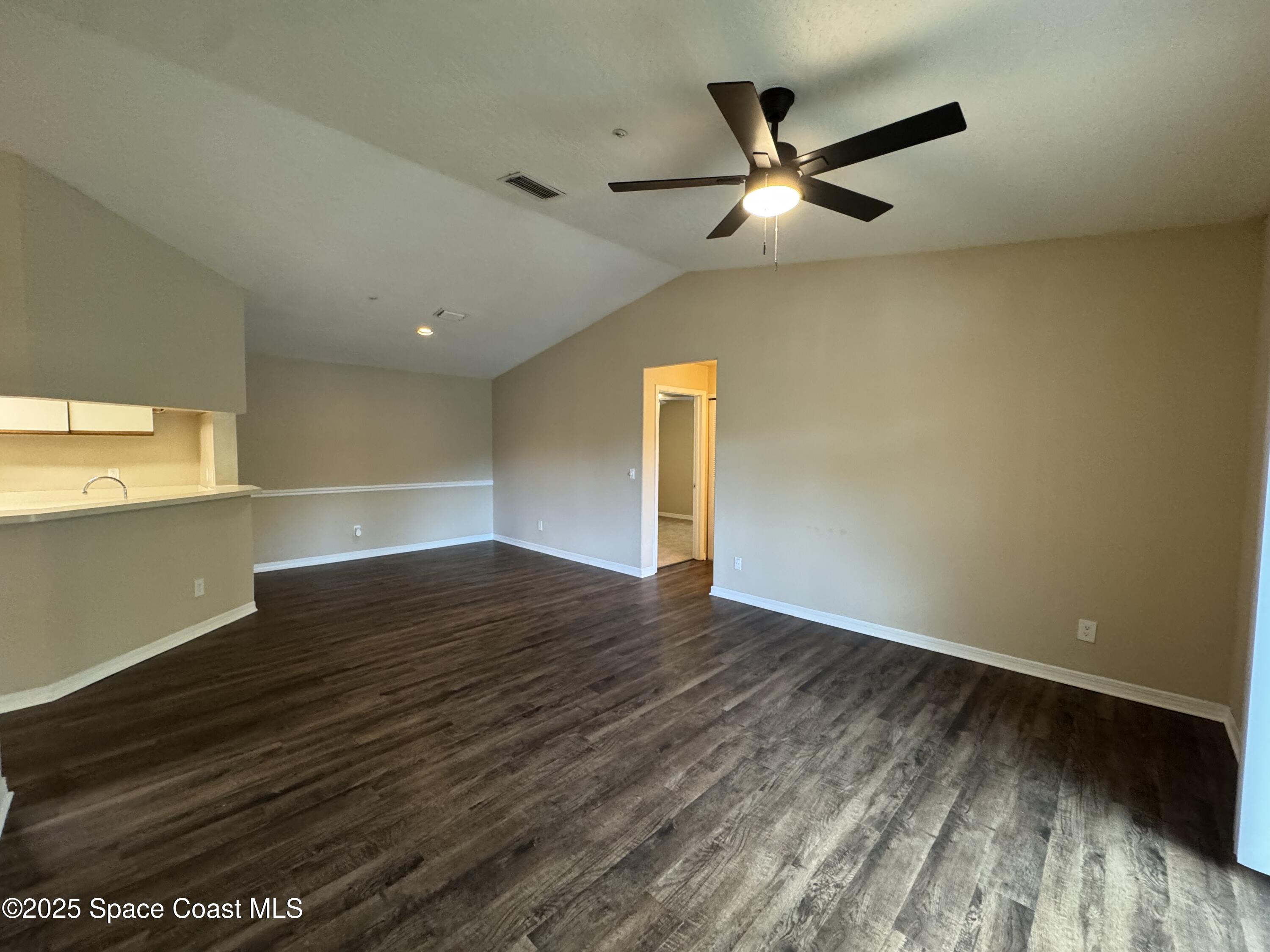 7667 North Wickham Road, Unit 1515 Melbourne, FL 32940 - Photo 10 of 36 a view of an empty room with wooden floor and a ceiling fan
