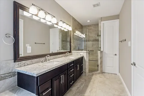 a bathroom with a granite countertop double vanity and a large mirror