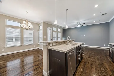 a kitchen with a stove a sink dishwasher and a wooden floor
