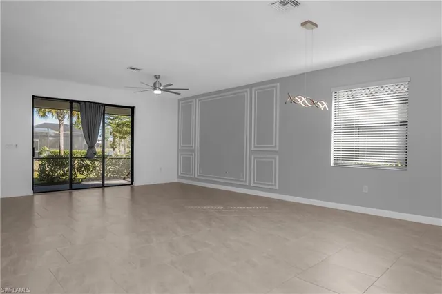 an empty room with windows and chandelier fan