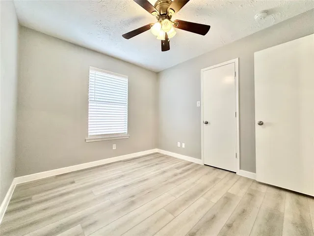 a view of an empty room with window and wooden floor