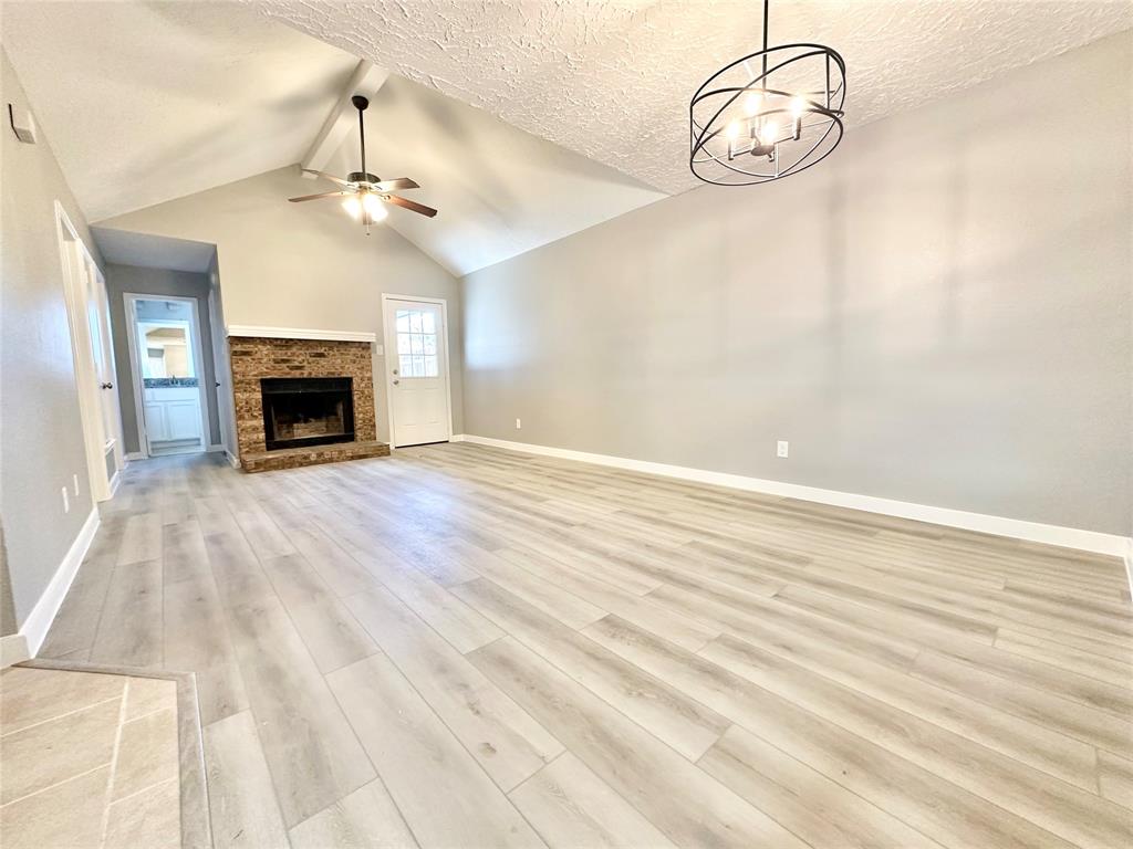 1002 Bull Run Street Denton, TX 76209 - Photo 2 of 21 an empty room with a fireplace and chandelier
