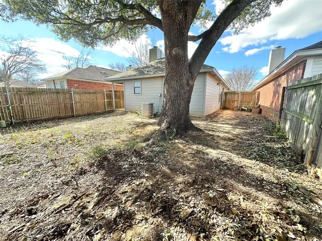 a view of a yard with wooden fence and a large tree