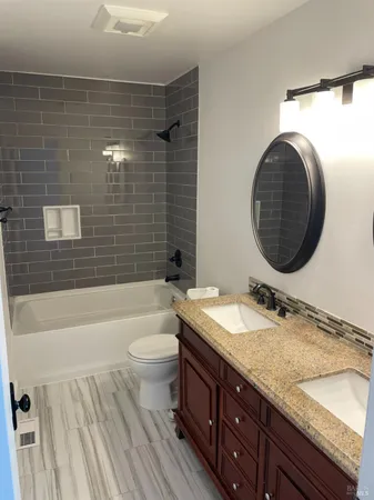 a bathroom with a granite countertop sink toilet mirror vanity and bathtub