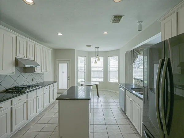 a large kitchen with kitchen island granite countertop a large counter top a sink a stove a refrigerator and cabinets