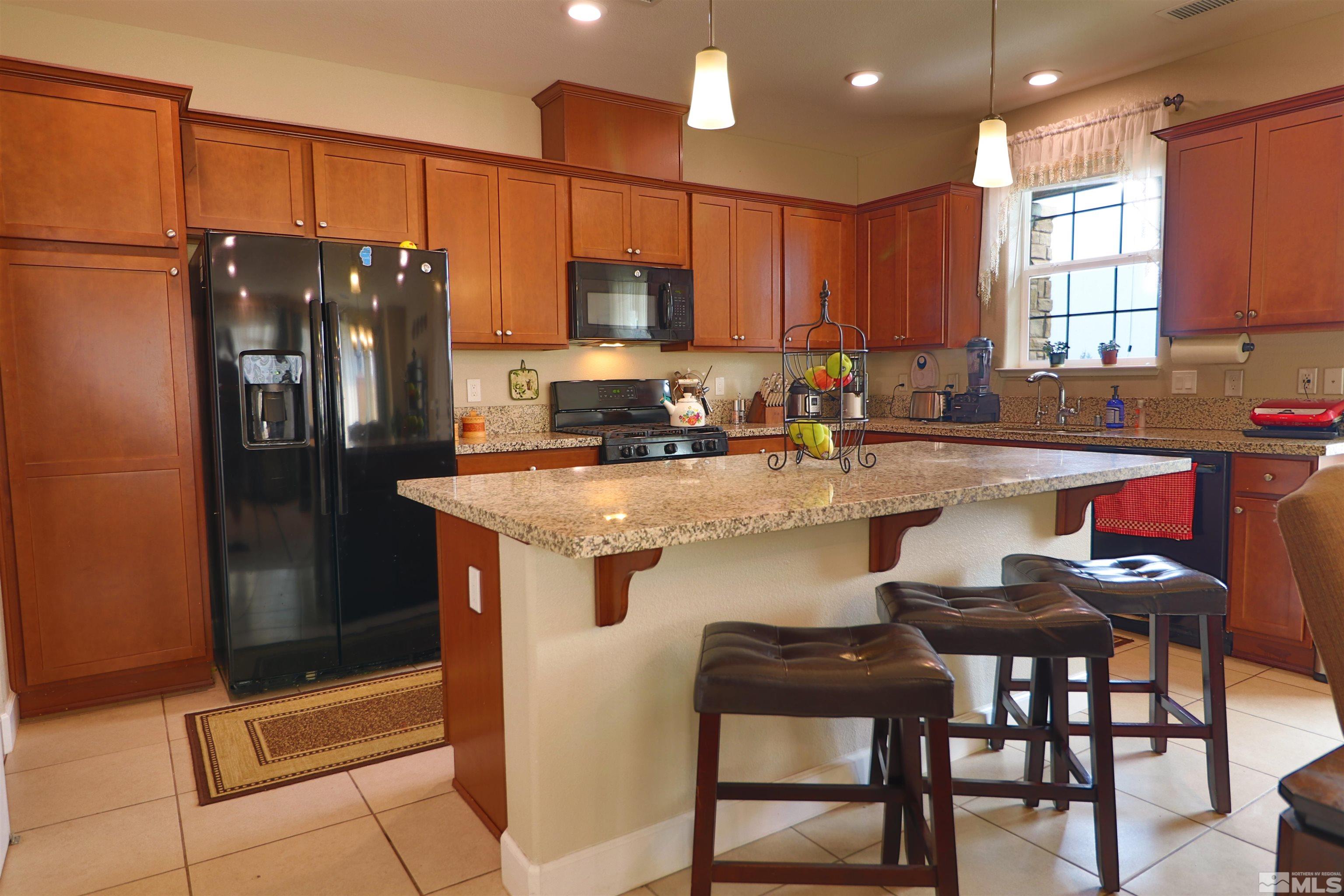 2037 Wind Ranch Road, Unit B Reno, NV 89521 - Photo 5 of 21 a kitchen with stainless steel appliances granite countertop a refrigerator a sink a stove a dining table and chairs