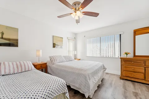 a view of a swimming pool with a lawn chairs under palm trees