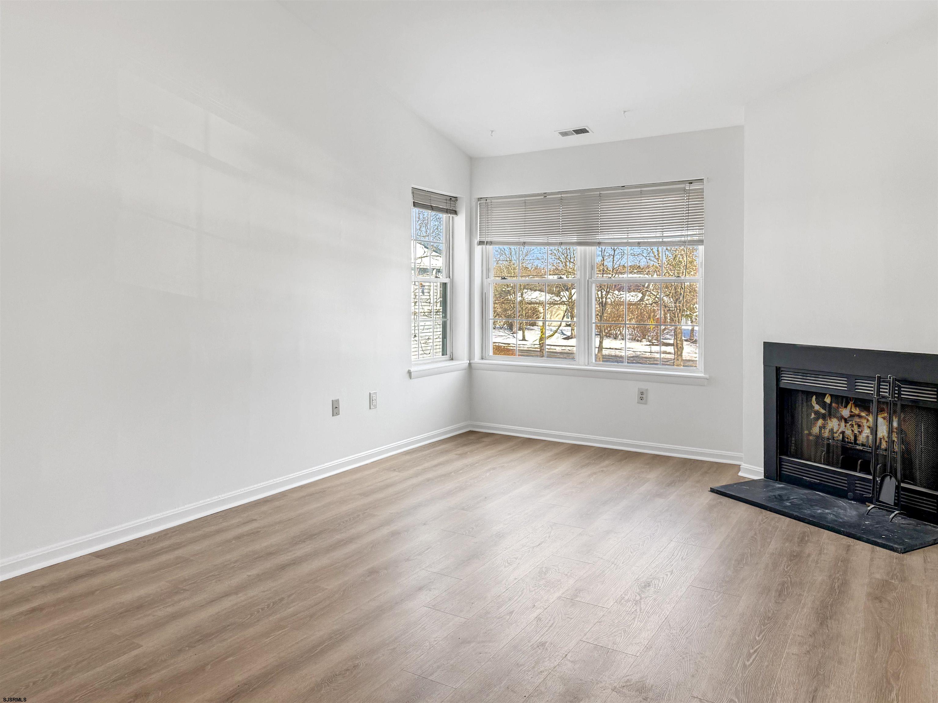 132 Meadow Ridge Road, Unit 132 Smithville, NJ 08205 - Photo 4 of 7 an empty room with windows and fireplace