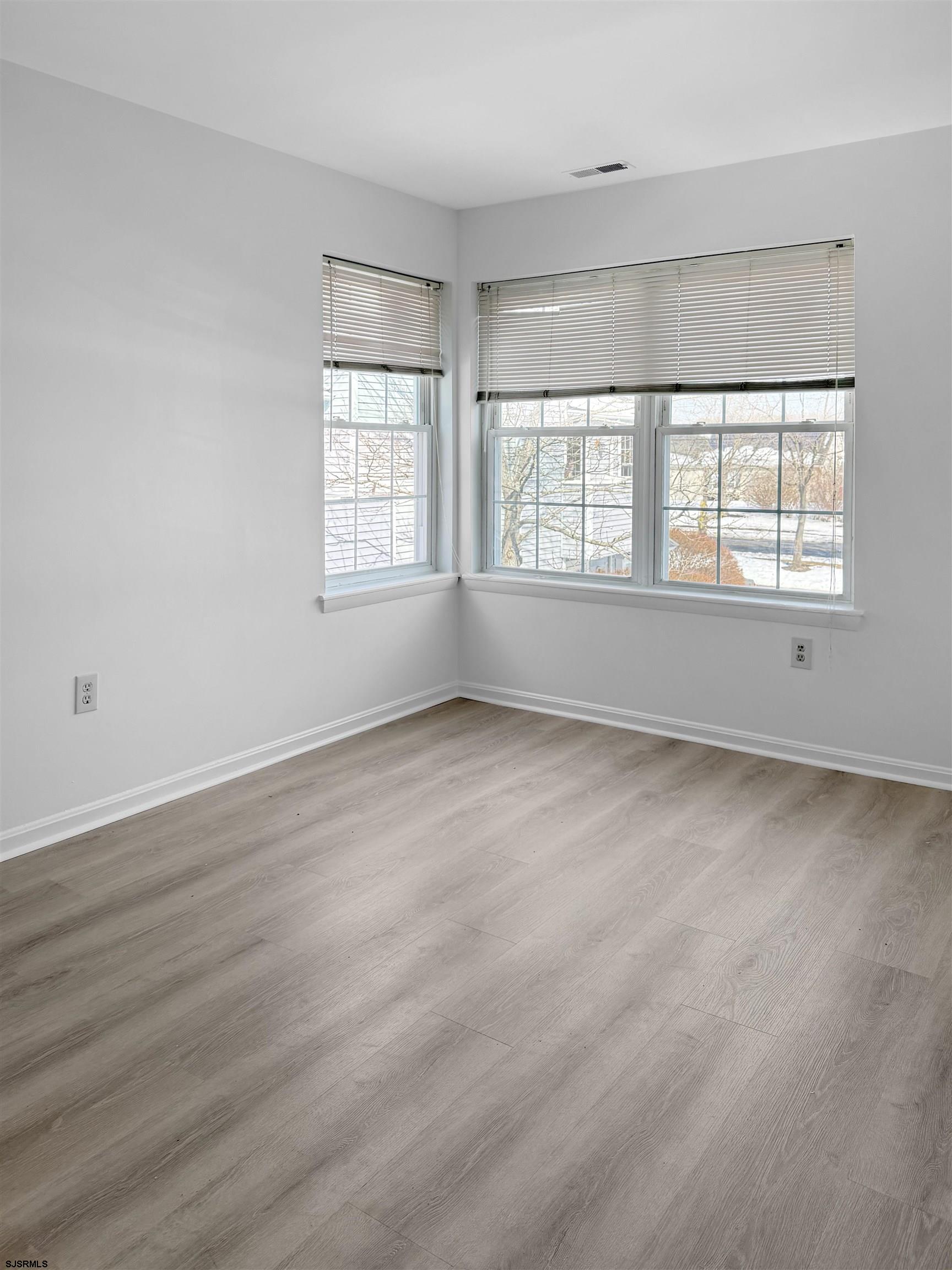 132 Meadow Ridge Road, Unit 132 Smithville, NJ 08205 - Photo 6 of 7 an empty room with wooden floor and windows