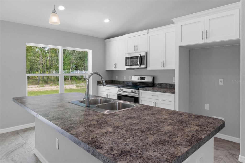 16375 Kakawi Road Brooksville, FL 34614 - Photo 10 of 30 a kitchen with kitchen island granite countertop a sink a stove a microwave a counter top space and cabinets