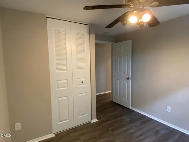 an empty room with wooden floor closet and windows