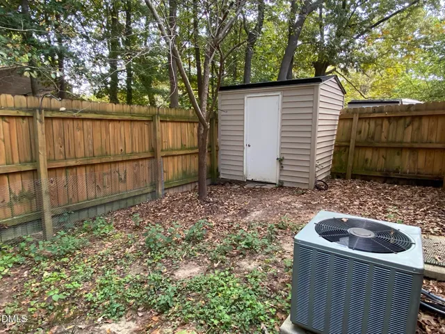 a view of backyard with small cabin and wooden fence