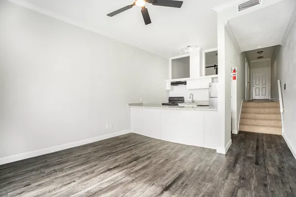 a view of kitchen and empty room with wooden floor