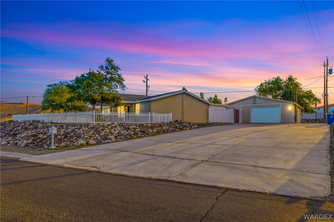 1996 Ramar Road Bullhead City, AZ 86442 - Photo 1 of 65 The property features a concrete driveway, a white picket fence, and a rock landscaping design