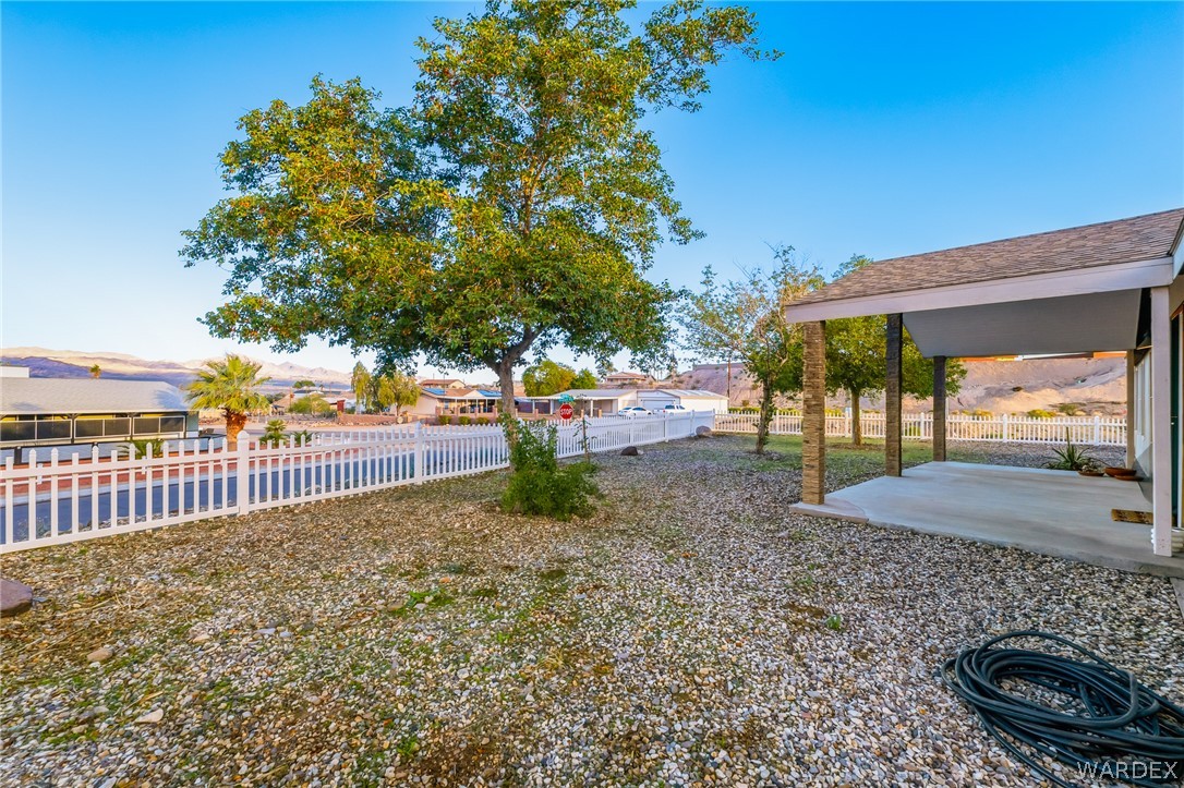 1996 Ramar Road Bullhead City, AZ 86442 - Photo 3 of 65 The property features a covered patio area with support columns, a gravel yard, and a mature tree
