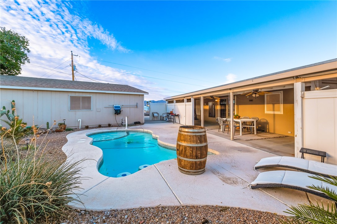 1996 Ramar Road Bullhead City, AZ 86442 - Photo 38 of 65 The property features a private swimming pool with a concrete surround, an expansive covered patio, and a gravel landscaped yard