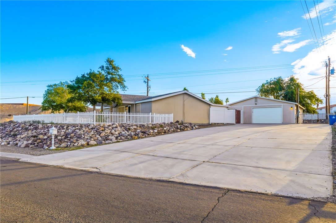 1996 Ramar Road Bullhead City, AZ 86442 - Photo 54 of 65 The property features a concrete driveway, a white picket fence, and a rock landscaping area