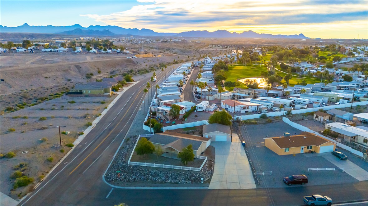 1996 Ramar Road Bullhead City, AZ 86442 - Photo 56 of 65 This aerial view showcases the property situated alongside a paved road, with a golf course and a body of water visible in the distance