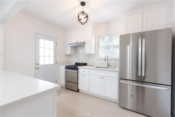 a kitchen with stainless steel appliances a refrigerator sink and white cabinets