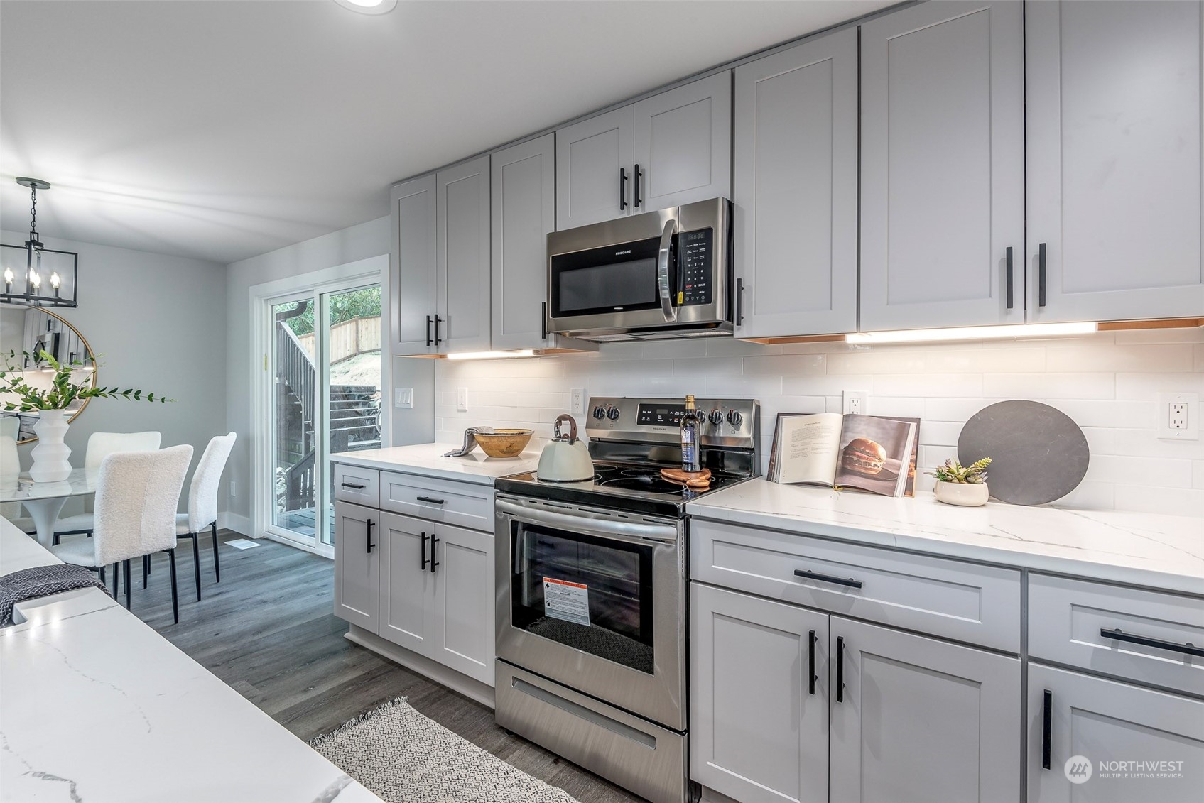 1582 Rainier Drive Fircrest, WA 98466 - Photo 14 of 40 a kitchen with stainless steel appliances granite countertop a stove a sink dishwasher and white cabinets with wooden floor