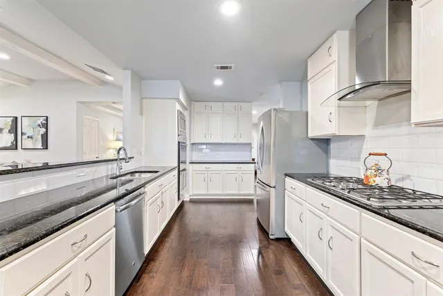 a large kitchen with stainless steel appliances granite countertop a lot of counter space and wooden floors