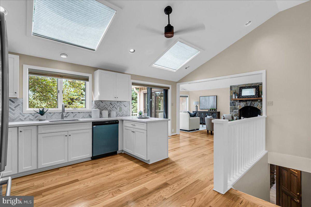 977 Wind Song Road West Chester, PA 19382 - Photo 13 of 57 a large white kitchen with a stove a sink dishwasher a microwave oven and a dining table with wooden floor