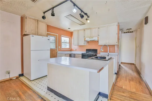 a kitchen with stainless steel appliances granite countertop a refrigerator a sink dishwasher a stove and white countertops with wooden floor