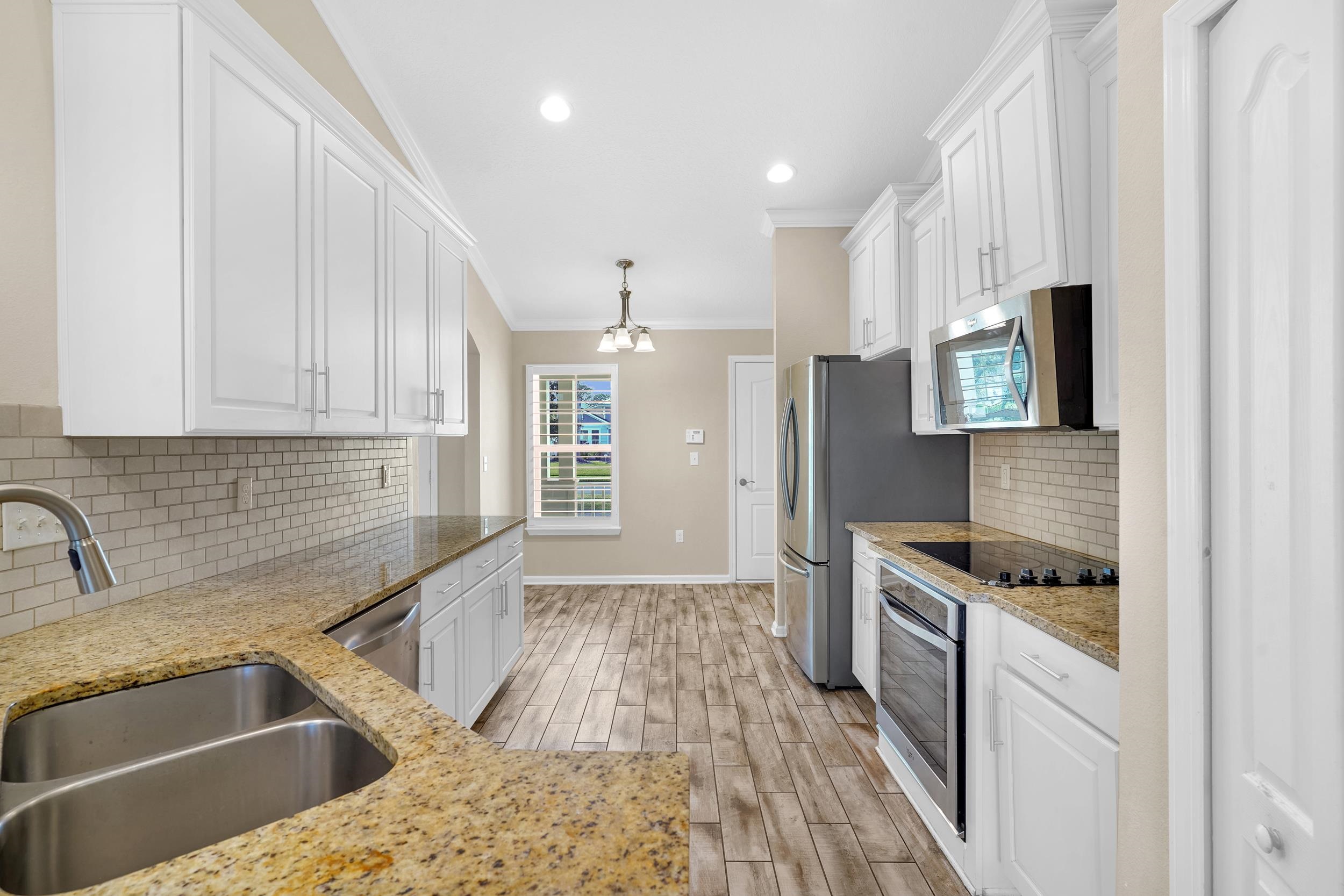 146 Ocean Cay Boulevard St. Augustine, FL 32080 - Photo 15 of 41 a kitchen with granite countertop a sink and a stove top oven with wooden floor