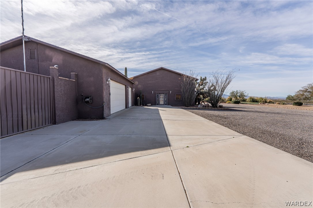 14158 Calabasas Road Yucca, AZ 86438 - Photo 24 of 99 Side view of garage featuring driveway and stucco siding