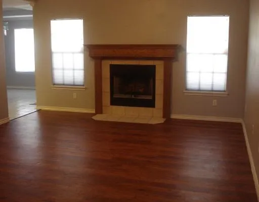 an empty room with wooden floor windows and fireplace