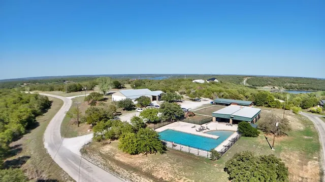a view of a patio with table and chairs under an umbrella with large trees