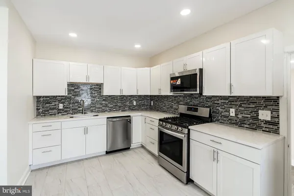 a kitchen with granite countertop white cabinets stainless steel appliances and sink
