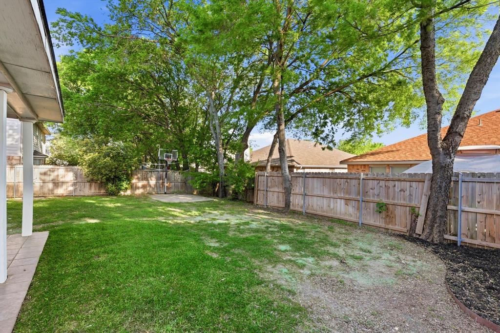 5512 Rocky Mountain Road Fort Worth, TX 76137 - Photo 30 of 33 a view of a backyard with large trees and wooden fence